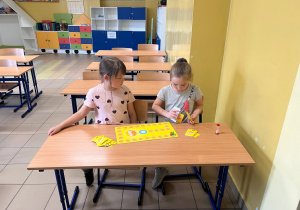 Dziewczynki siedząc w ławce grają w grę na czas