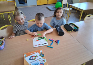 Dzieci układają figury geometryczne po śladzie za pomocą klocków