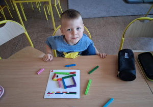 Dziecko ułożyło figury geometryczne po śladzie za pomocą klocków